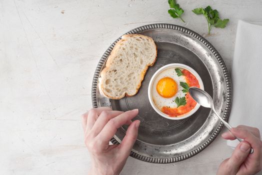 Eating eggs baked with tomatoes and parsley  top view