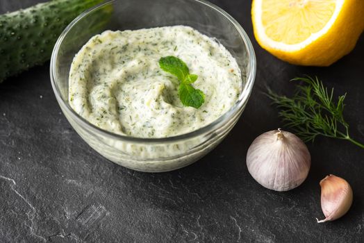 Tzatziki  on the black stone table with ingredients
