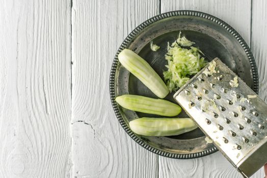 Grated and whole cucumber in the metal plate top view