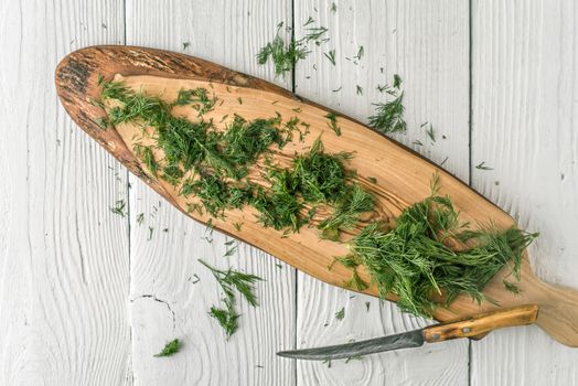 Dill on the natural wooden board on the white table top view