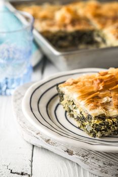 Greek pie spanakopita in the ceramic plate on the white  table  vertical