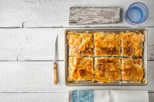 Greek pie spanakopita in the metal pan  with table ware horizontal