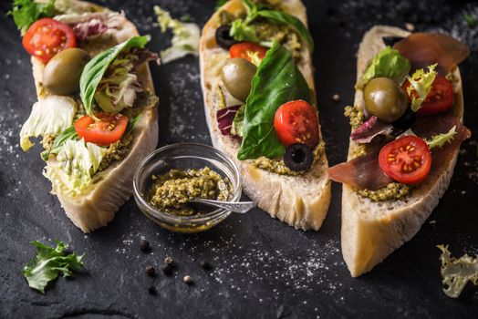 Ciabatta with olives , tomatoes and basil on the black stone table