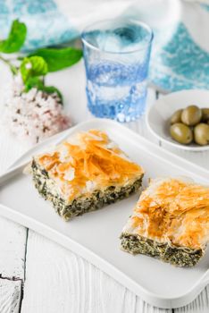 Greek pie spanakopita on the white plate with accessorizes vertical