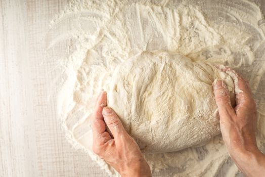 Dough  in the hand on the table with flour top view