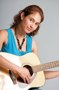 Pretty multi-ethnic brunette playing a acoustic guitar