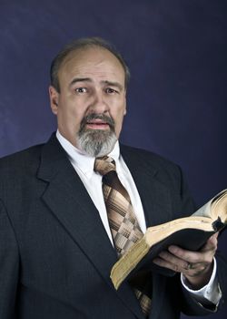 Mature male reading from a Bible and preaching.