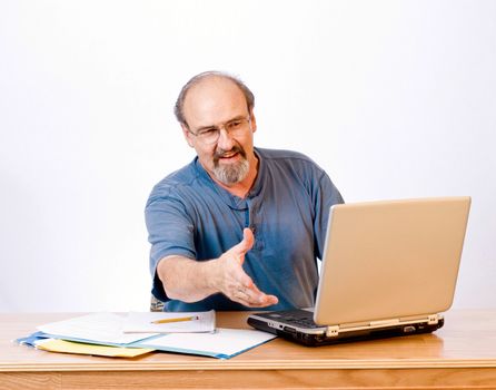 Businessman reaching to shake the hand of a client across his desk.