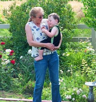 Grandmother having fun with grandson in her garden with a pulled weed.