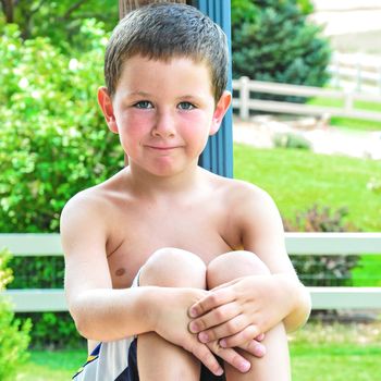 Smiling boy resting on the porch railing after playing.