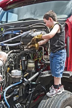 Cute little boy checking the oil on his parents semi-truck.