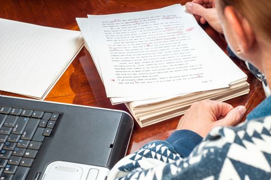 Woman author re-writing her manuscript after it has been proofread by an editor.