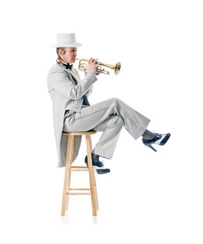 Pretty woman in a tuxedo and top hat playing blues on a trumpet while seated.
