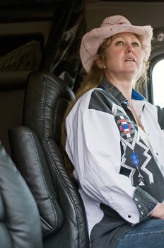 Blonde woman truck driver checking the road ahead as she drives across country in a semi-truck.