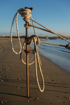 A rope of a boat is tie up with iron stake on the beach