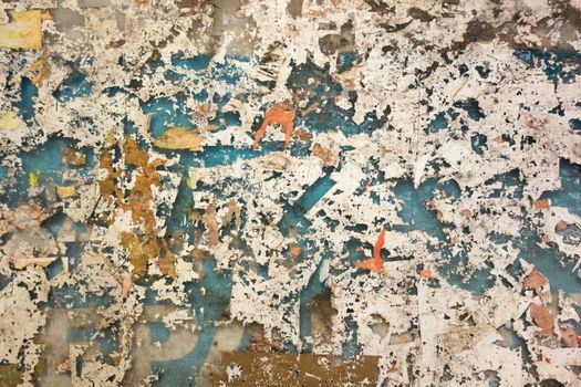 Colorful torn posters on old wall. Grunge textures and backgrounds