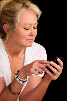Mature woman smiling as she texts on her cell phone.