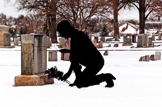 Grieving woman placing flowers on her deceased husbands grave.