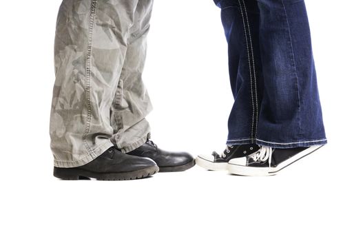 Feet and lower legs of a man and a woman as they kiss with her up on her toes.