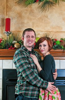 Happy couple spending time together in front of the fireplace at Christmas.