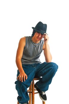 Handsome young man sitting cool in a fedora on a stool. Isolated on a white background.