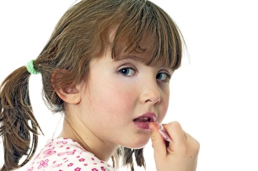A little girl putting on lip gloss