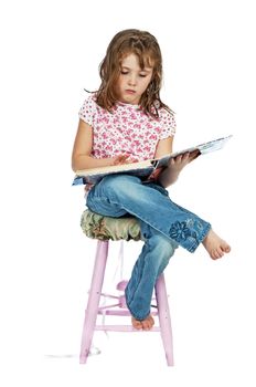 Little girl reading while seated. Isolated on a white background.