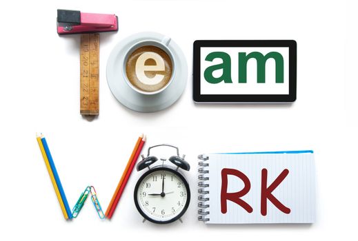 Team work spelt using stationery office tools including a digital tablet, clock and notepad