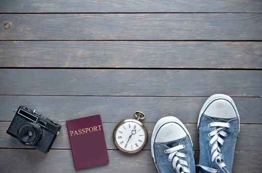 Travel essentials including passport and camera with space for text on a wooden background