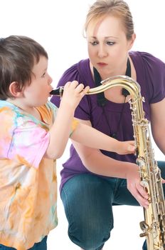 A saxophone playing young woman letting her son blow into the instrument.