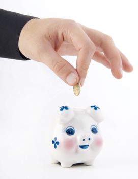 Hand inserting coin into piggy-bank