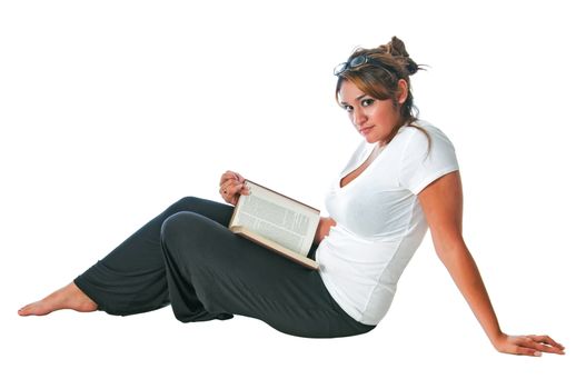 Pretty young girl reading a book while seated on the floor. Isolated on a white background
