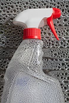 Transparent spray cleaner bottle isolated on water drops