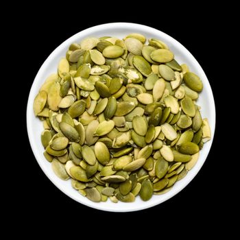 Pumpkin seeds in plate isolated on black background