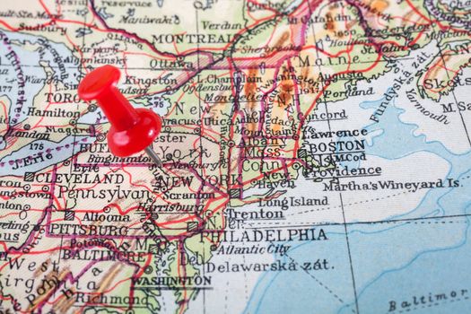 Red push pin showing the location of a destination point on a map. New York