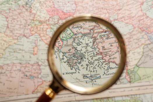 Magnifying glass in front of a Greece map
