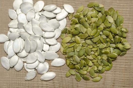 Two handfuls of peeled and inshell, pumpkin seeds, stands on the old boards.