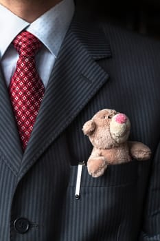 The elegant stylish businessman keeping cute teddy bear in a his breast suit pocket. Formal negotiations concept