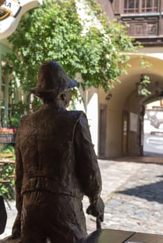 View from the back side of a miner statue,part of the Mining Museum in the city Banska Stiavnica in Slovakia. Yard of a house with a green bush.