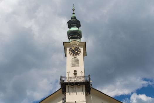 Former mining city Banska Stiavnica, Slovakia and its town hall with a tower and clock. City is part of UNESCO World Heritage Site. Cloudy sky.