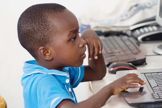 This child is focused on his work at the computer.