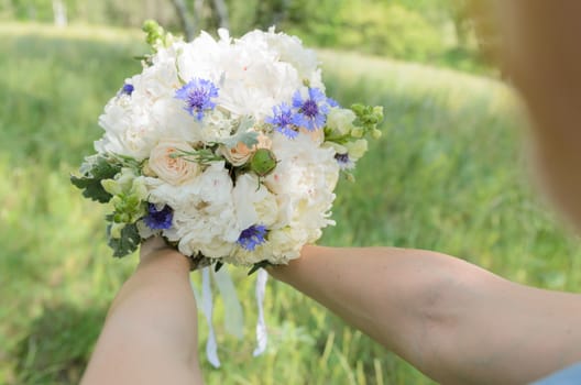 bride with a bouquet in green grass