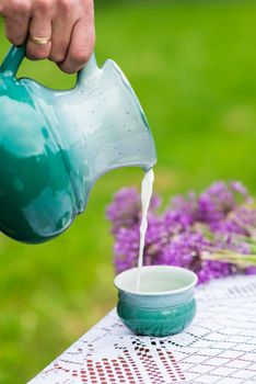 Milk being poured into turquoise cup from ceramic pot