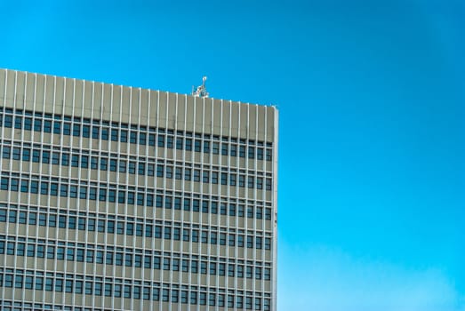 horizontal image of cement tall building with windows and the sky