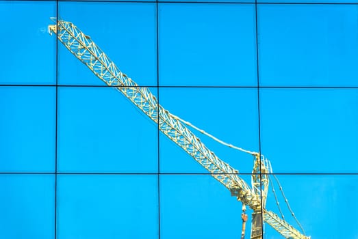 crane reflection over a building with blue sky