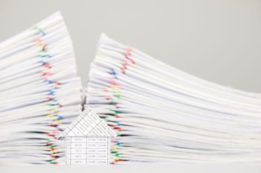 House on white table have blur pile overload of paperwork with colorful paperclip as background.