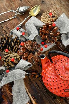 Red metal teapot,tea leaves and autumn pine cones