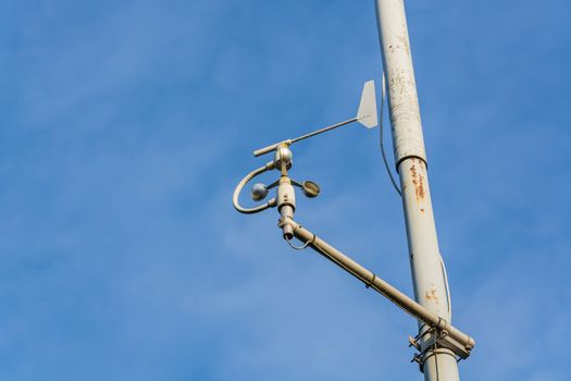 Weather station with anemometer on blue sky.