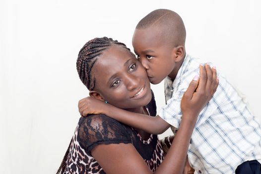 A Child giving a kiss to his mother who is very happy .