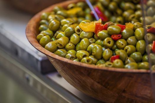 Close-up of green olives with red and yellow pepperoni in a dish